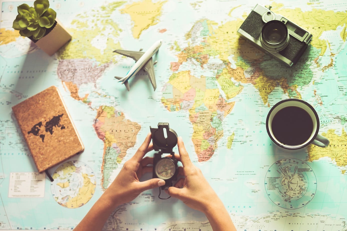 Young woman drinking coffee and planning world tour with vintage travel map – Backpacker girl looking for a new countries to explore – Journey trends, globetrotter and holiday concept – Focus on mug