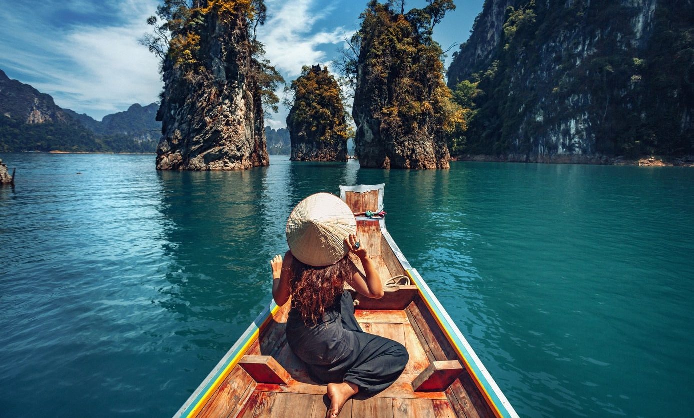young woman tourist in asian hat on the boat at lake